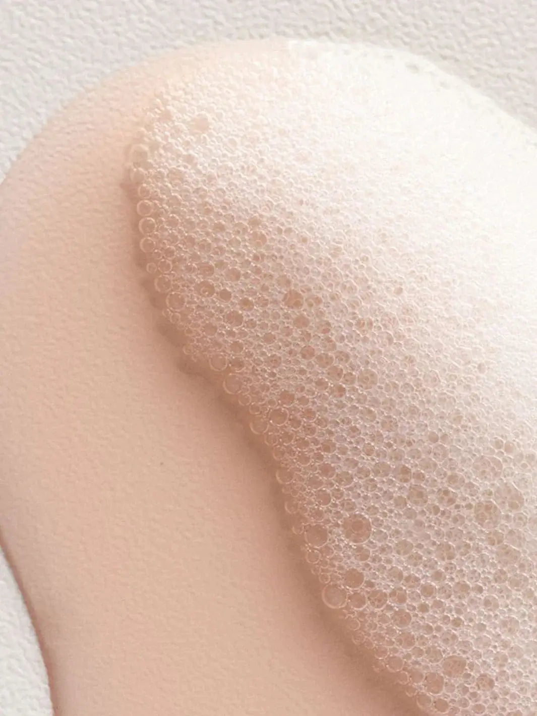 A close-up shot shows a peach-colored liquid, thick, bubbly white lather from Davines ENERGIZING Shampoo | Twentyseven Toronto