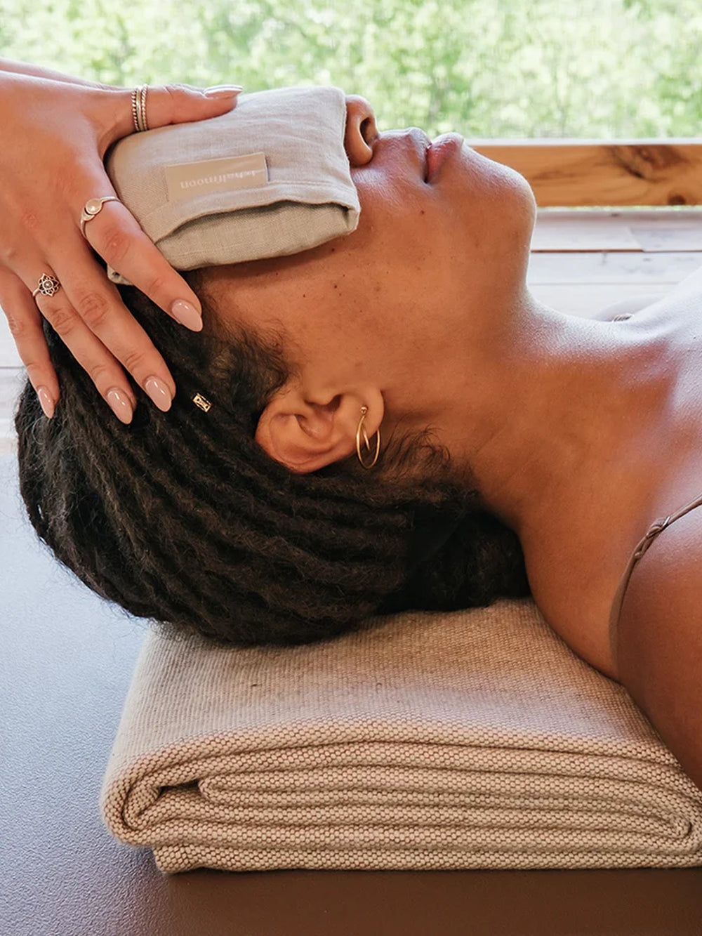 1. Person relaxing with the b, halfmoon Linen Eye Pillow held gently over their eyes | Twentyseven Toronto