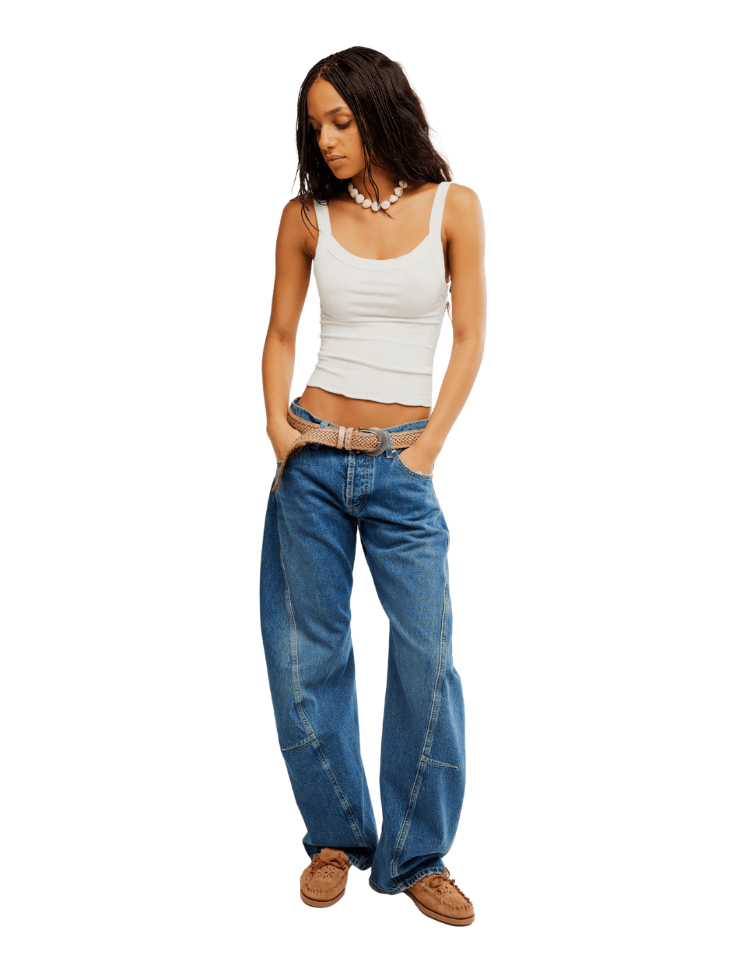 A model with braided hair wearing the Free People Fable Twisted Seam Jean in Heartsong, a white tank top, and a woven belt | Twentyseven Toronto
