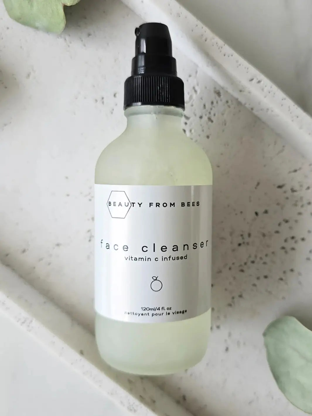 Bottle of 'Beauty From Bees' Face Cleanser on a textured surface | Twentyseven Toronto