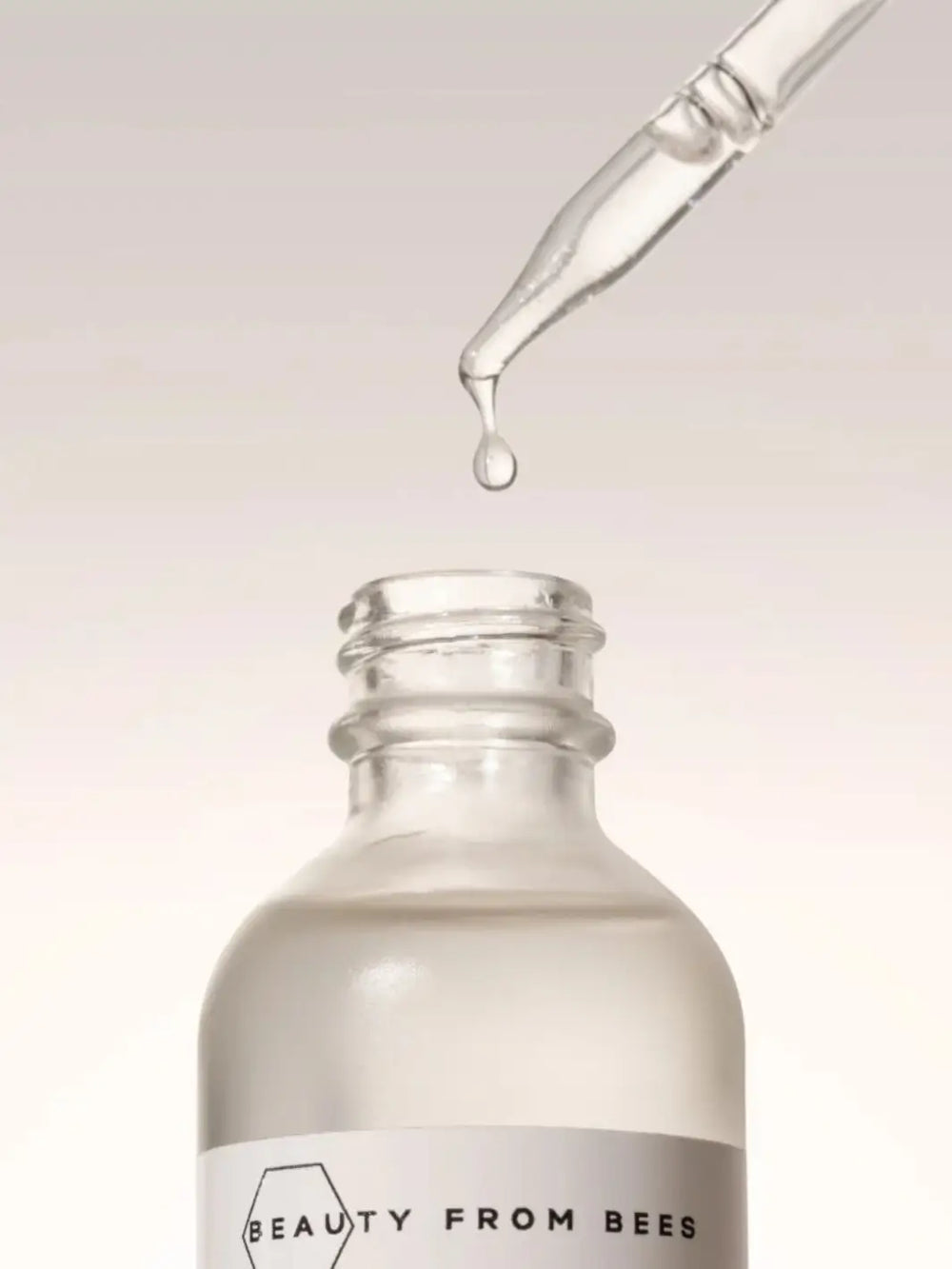 Skincare dropper bottle with droplet of Beauty from Bees Face Oil on a neutral background, featuring 'Beauty from Bees' branding | Twentyseven Toronto