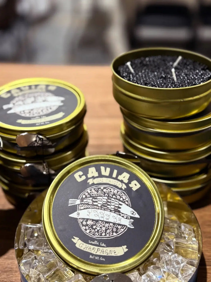 Gold tins of Fancy Caviar Candle from Tinned Fish Candles on a wooden surface | Twentyseven Toronto