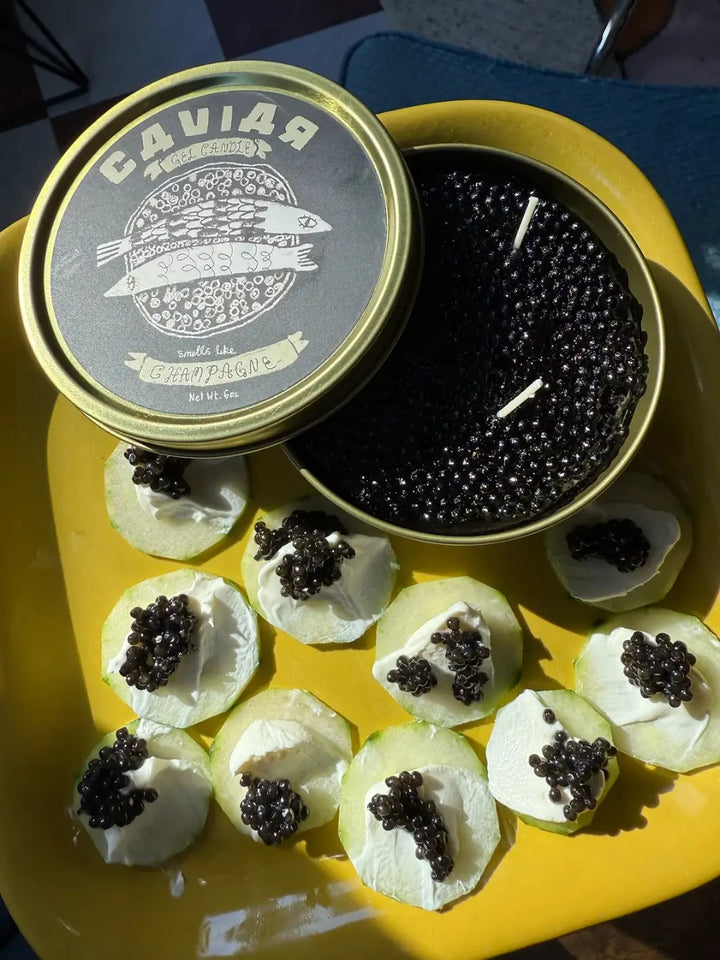Fancy Caviar Candle in a gold and black tin from Tinned Fish Candles on a yellow plate | Twentyseven Toronto