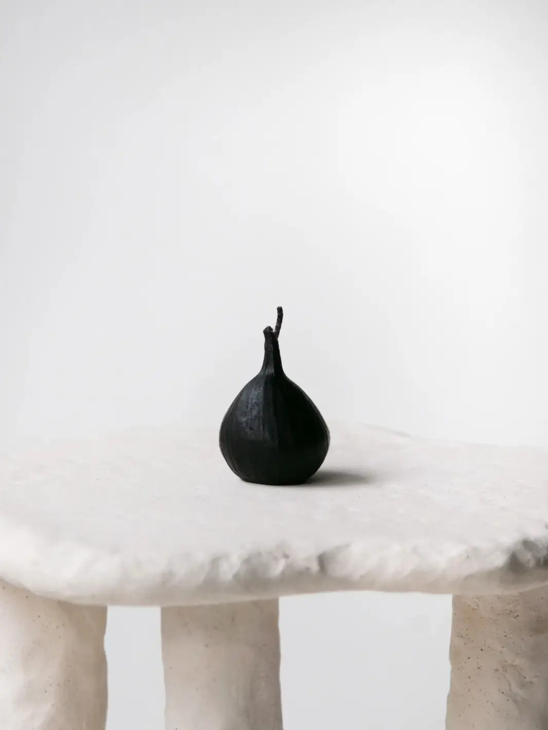 Fig-shaped beeswax candle from Happy Organics on a white textured table | Twentyseven Toronto
