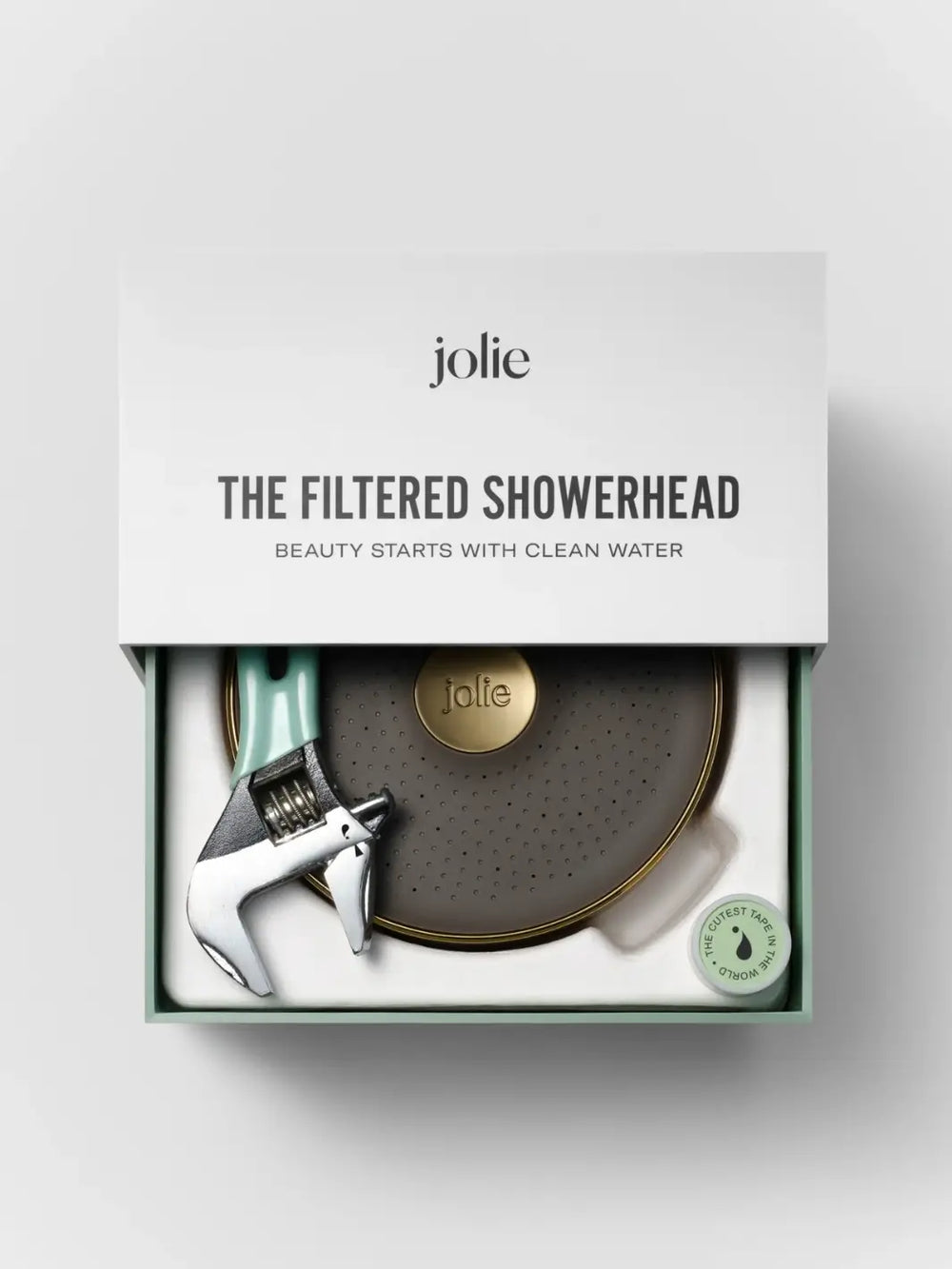 An open white and green branded box displaying the unboxed Jolie Skin Co The Filtered Shower Head - Brushed Gold alongside an included installation wrench and a small roll of plumber's tape | Twentyseven Toronto