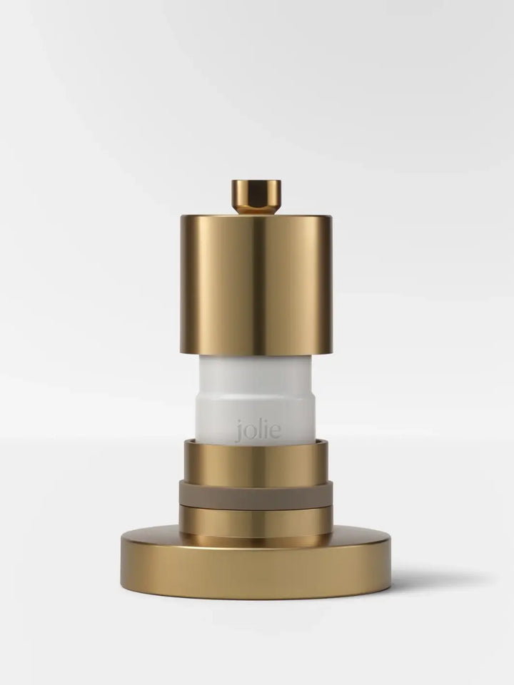 A disassembled, cross-sectional studio shot highlighting the internal white replacement filter inside the metallic body of the Jolie Skin Co The Filtered Shower Head - Brushed Gold | Twentyseven Toronto