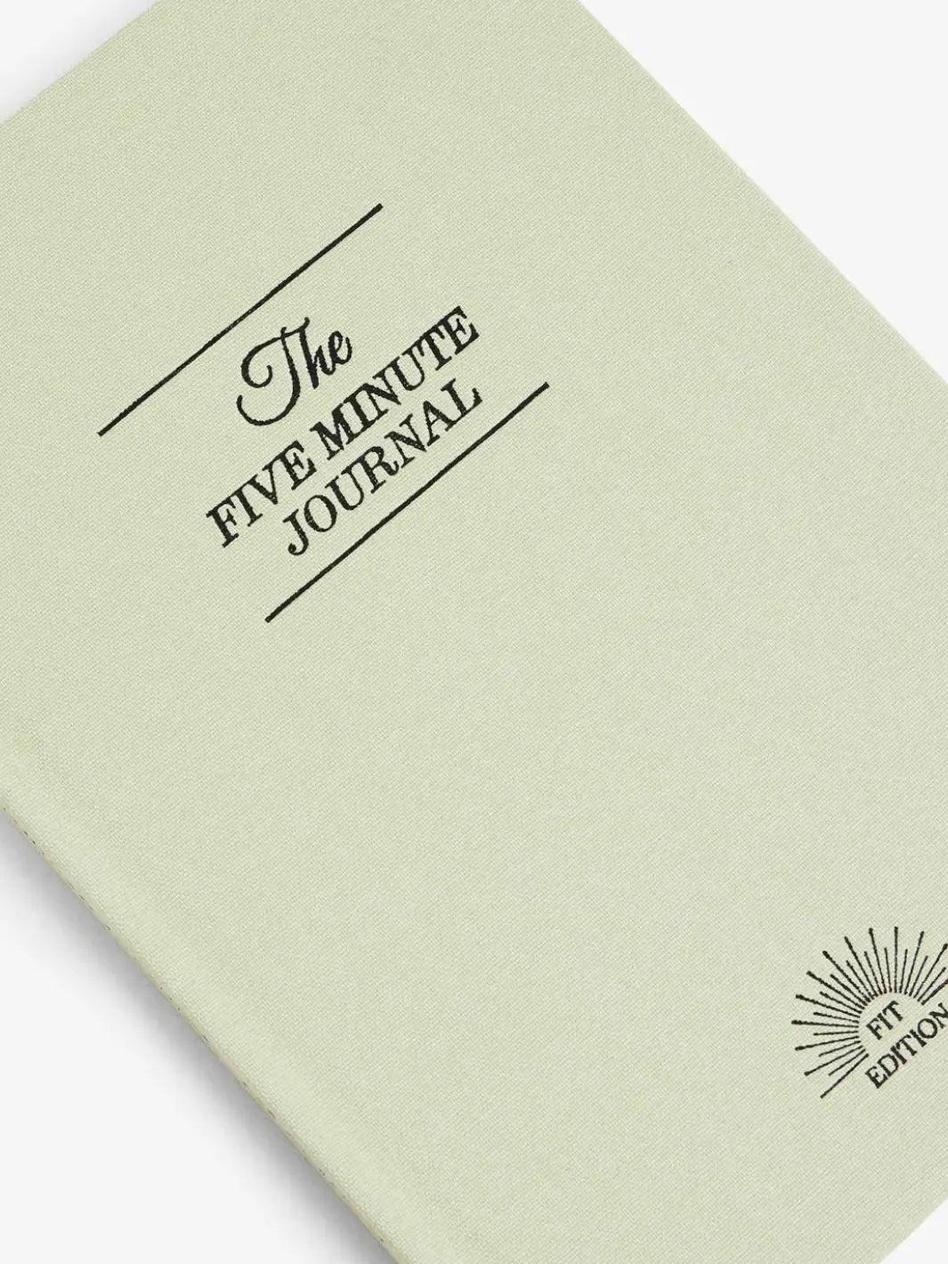 A close-up shot focuses on the cover text and "Fit Edition" logo embossed on the front of the light green Intelligent Change The Five Minute Journal Health & Fitness Edition | Twentyseven Toronto