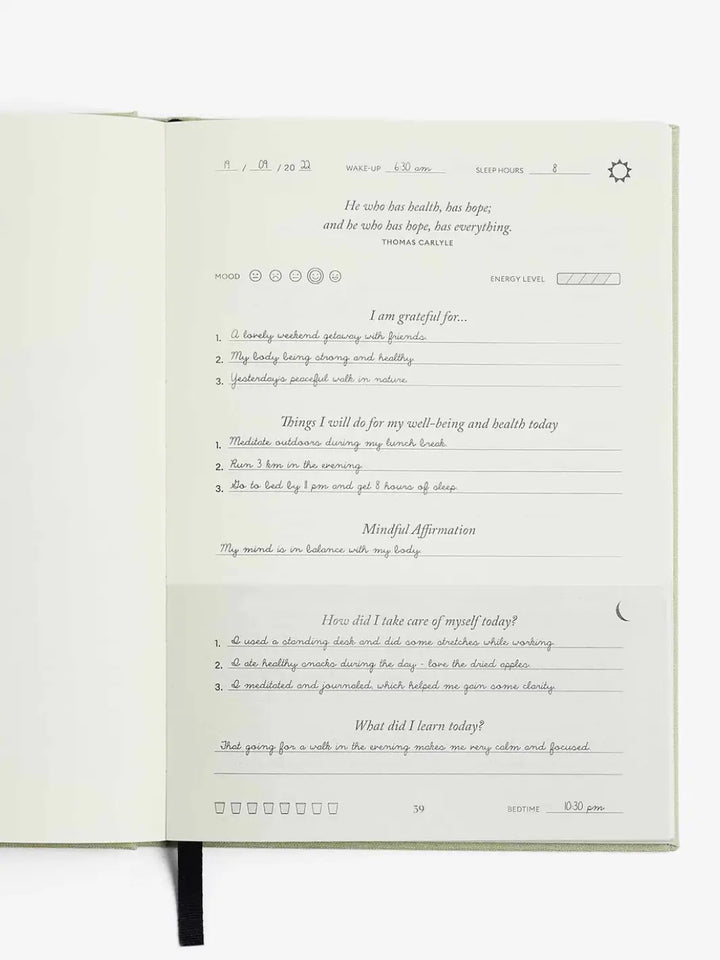 An open page of the Intelligent Change The Five Minute Journal Health & Fitness Edition displays completed handwritten daily entries for morning gratitude, daily wellness tasks, and evening reflection | Twentyseven Toronto
