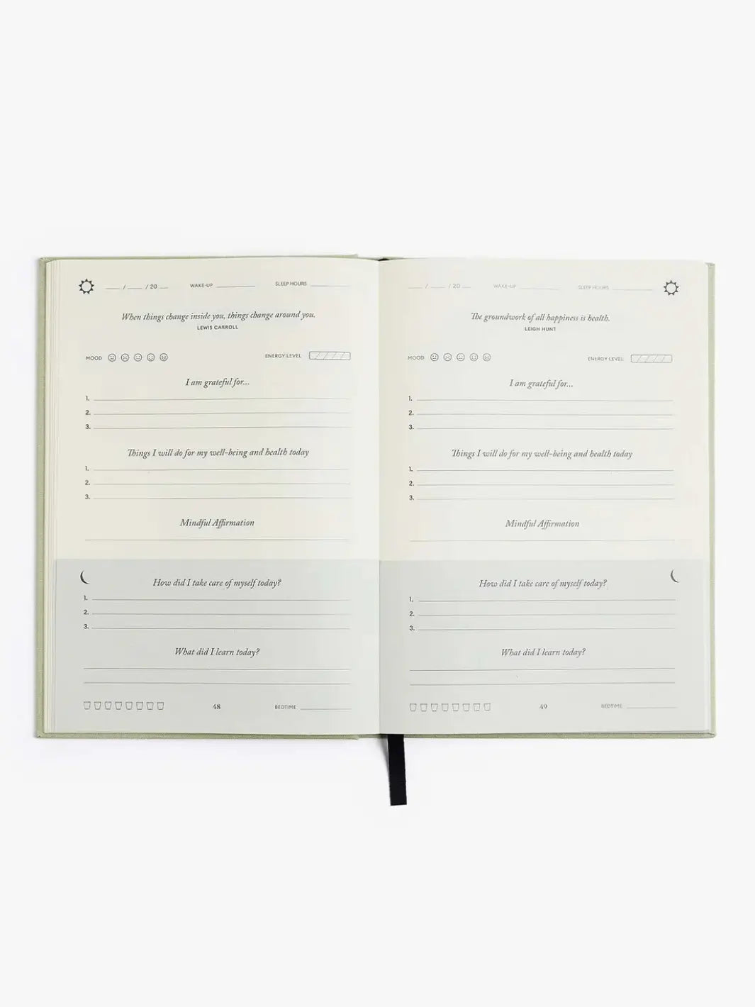 A flat lay view shows two blank daily tracking pages inside the open Intelligent Change The Five Minute Journal Health & Fitness Edition against a plain white background | Twentyseven Toronto