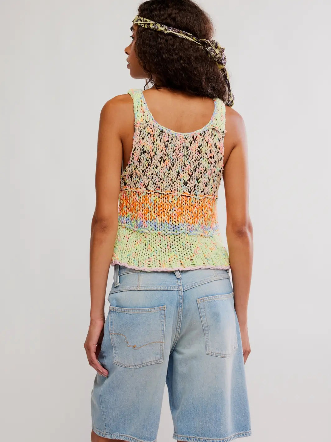 Woman wearing a colorful 'Flea Market Knot Tank' sleeveless top in 'Paradise Combo' and denim shorts from Free People on a white background, back view | Twentyseven Toronto