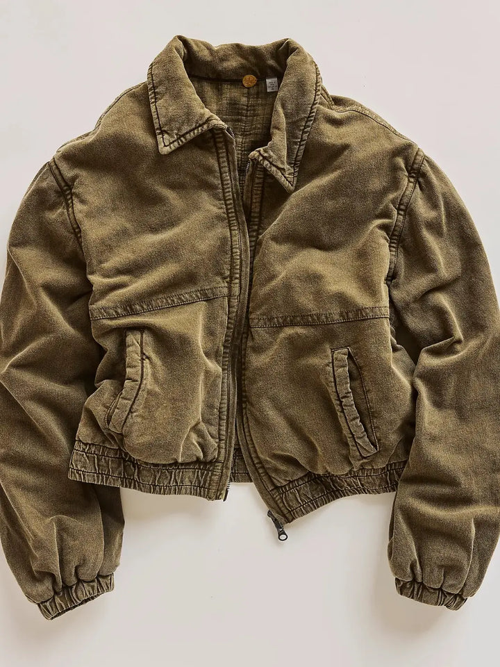 An olive green corduroy FP One Birdie Washed Jacket from Free People with a zippered front, collar, and elasticized cuffs, laid flat against a light off-white background | Twentyseven Toronto