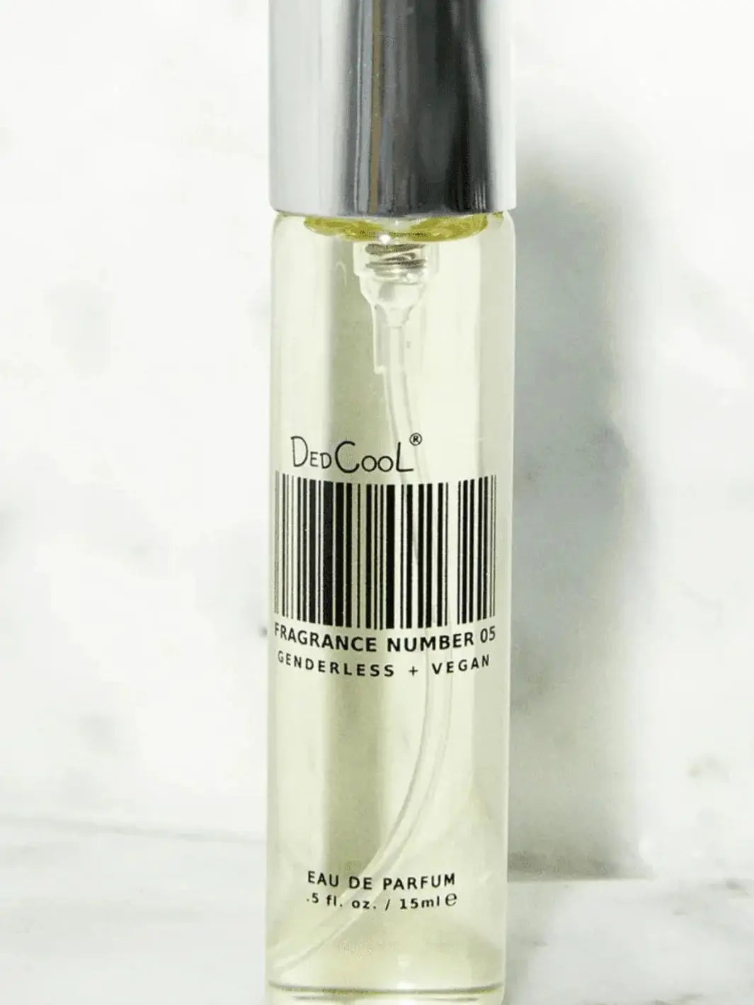 A slim, 15ml travel-size spray bottle of Dedcool Fragrance 05 "Spring" stands upright against a light textured backdrop | Twentyseven Toronto