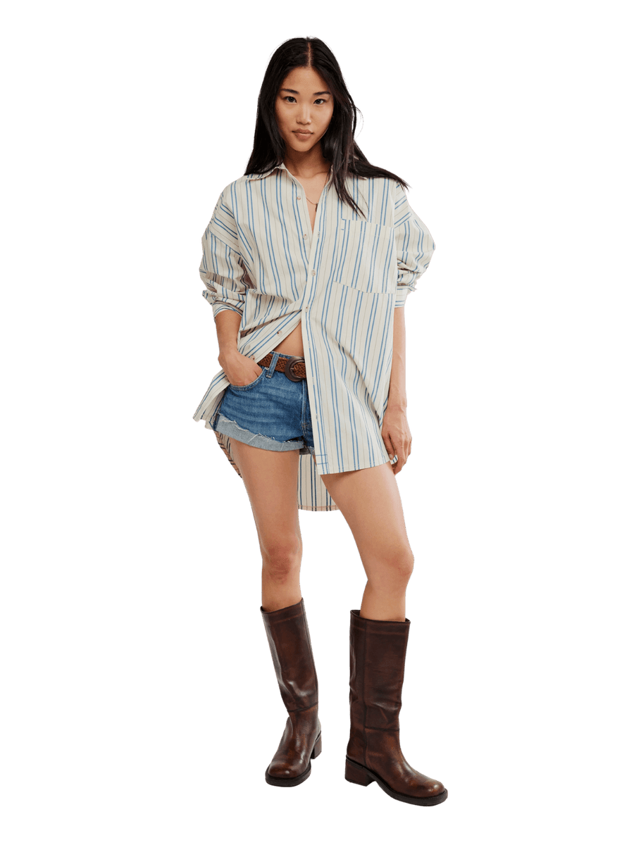 A model wearing the oversized, vertically striped Free People We the Free Freddie Striped Shirt in Ivory Combo paired with denim shorts | Twentyseven Toronto