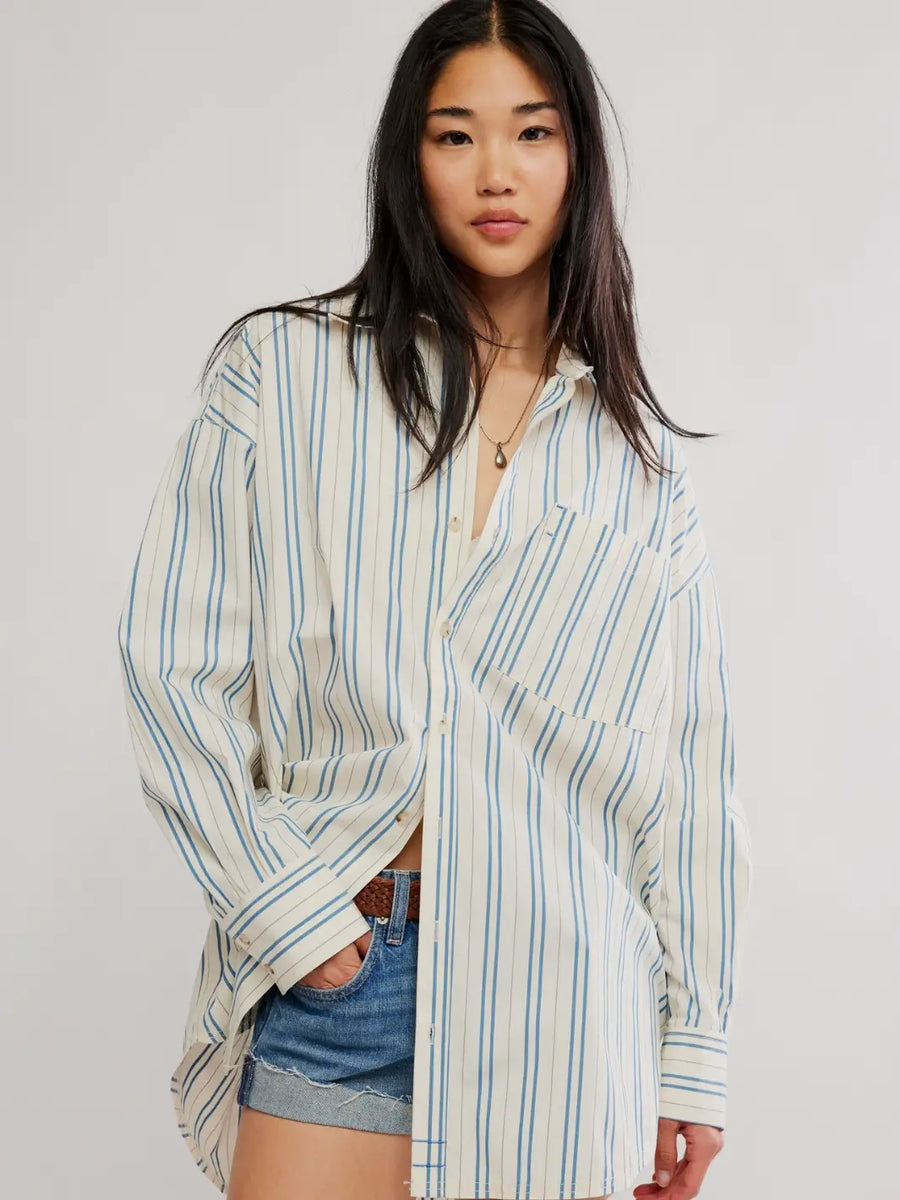 A model wearing the oversized, vertically striped Free People We the Free Freddie Striped Shirt in Ivory Combo paired with denim shorts | Twentyseven Toronto
