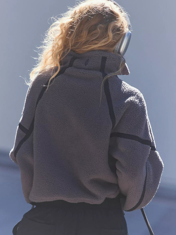 Back view of model wearing a charcoal grey sherpa half-zip pullover with black trim, paired with black wide-leg pants and oversized headphones in outdoor sunlight | Twentyseven Toronto