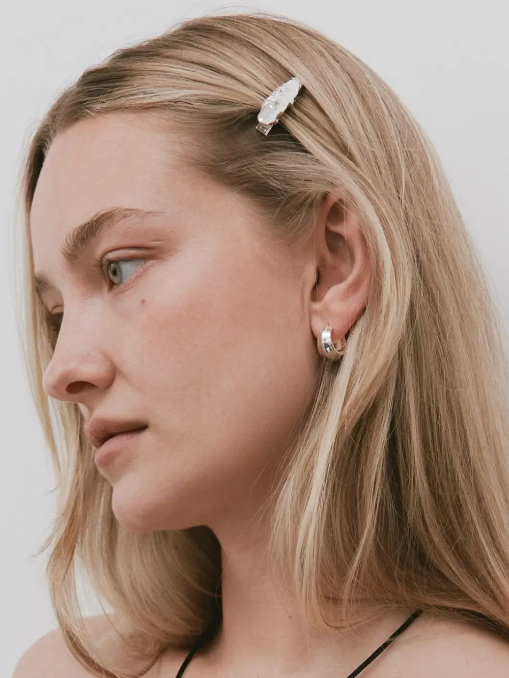 A woman with blonde hair wearing a silver textured Frida Clip in Silver from Wolf Circus pinning back a section of her hair above the ear | Twentyseven Toronto