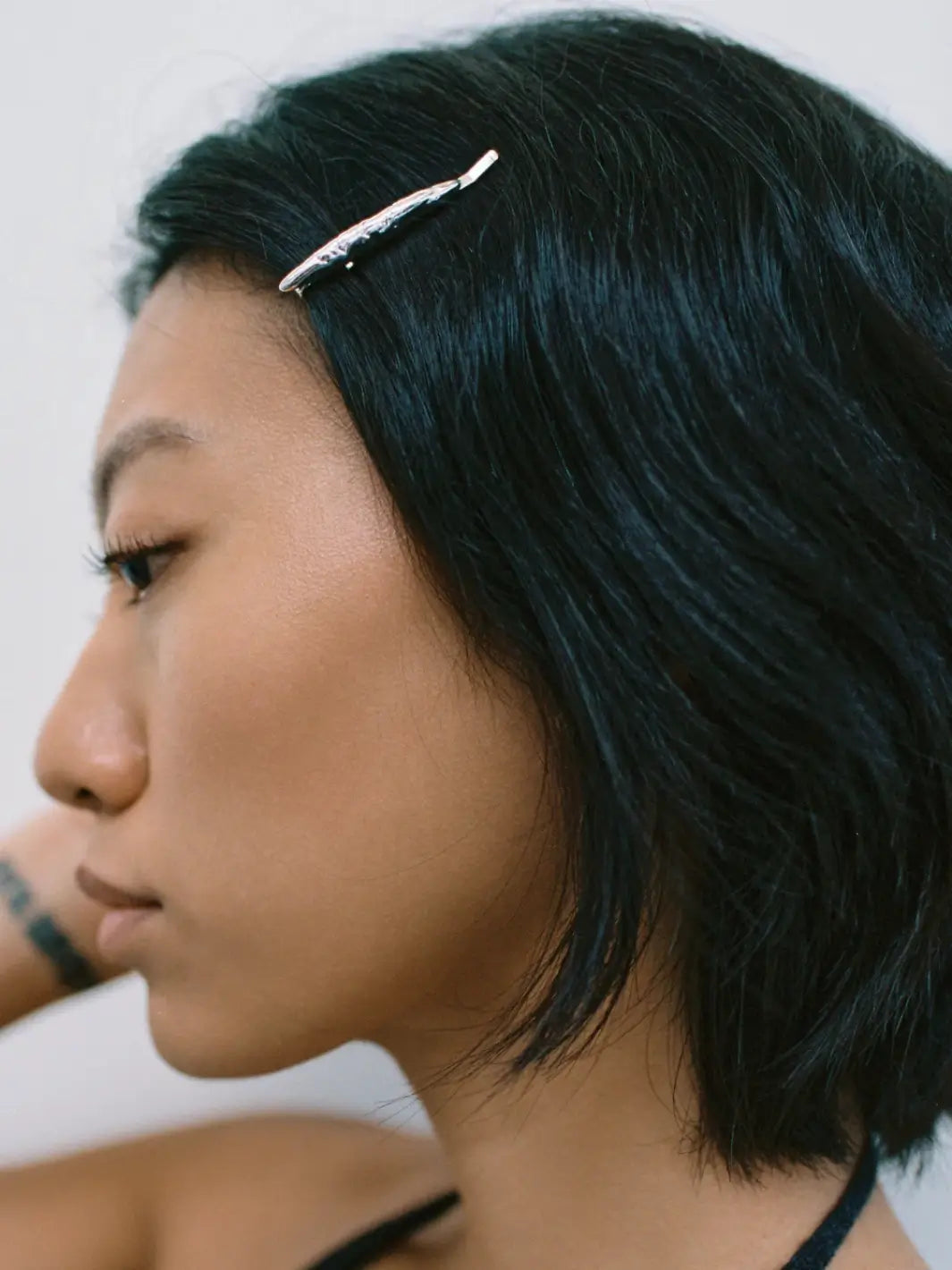 A side view of a woman with dark hair wearing a single textured, metallic Frida Pin in Silver from Wolf Circus | Twentyseven Toronto