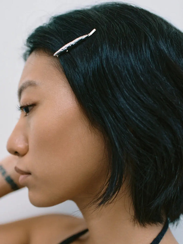 A side view of a woman with dark hair wearing a single textured, metallic Frida Pin in Silver from Wolf Circus | Twentyseven Toronto