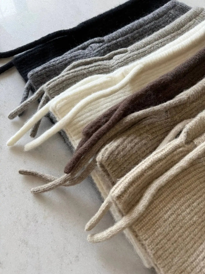 A close-up, angled view highlights the soft, fuzzy texture and adjustable drawstrings of six different colored Billy Bamboo Fuzzy Alpaca Balaclava hoods arranged in a neat row | Twentyseven Toronto