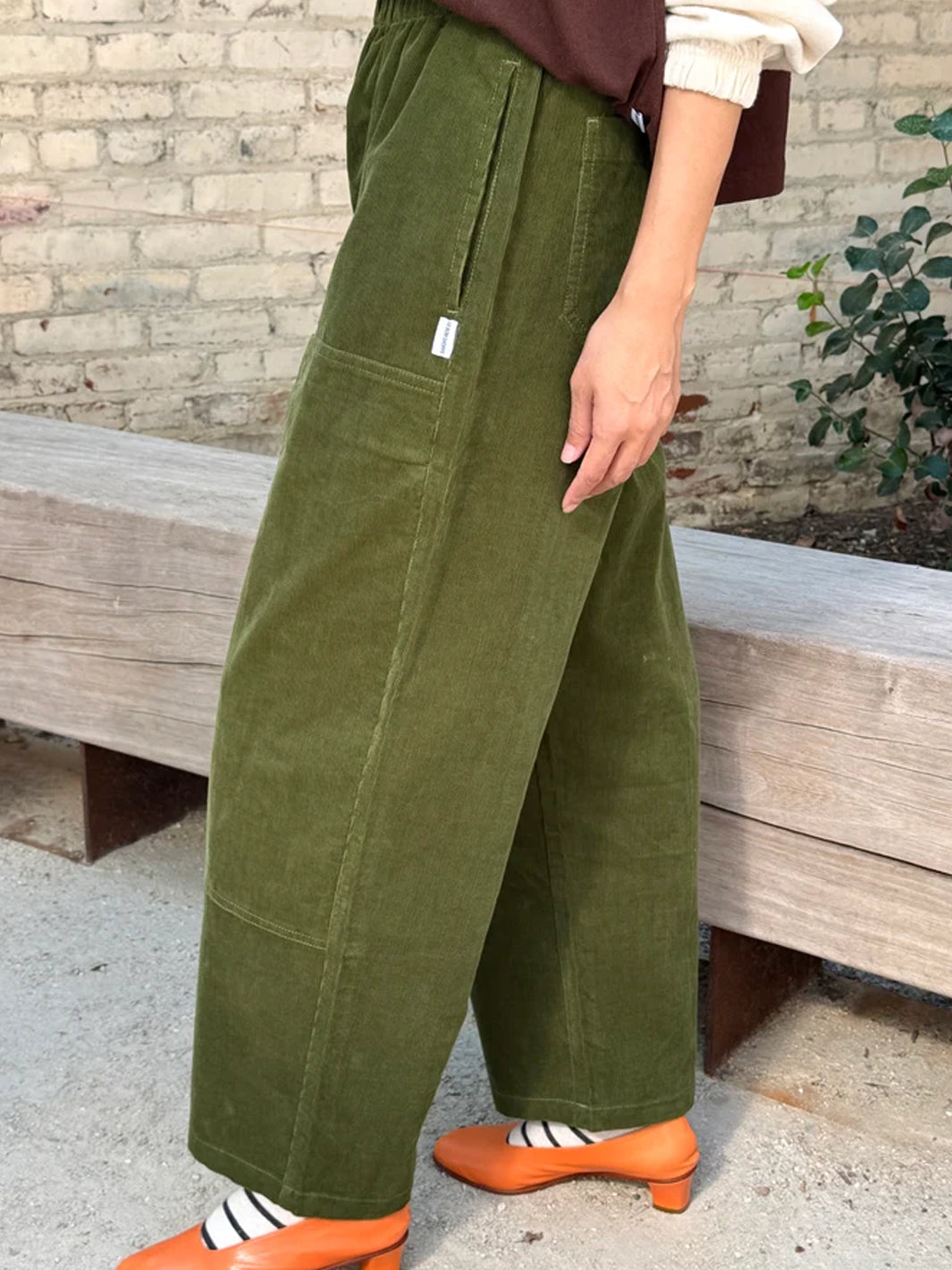 Side view of Le Bon Shoppe Corduroy Gardener's Pants in Bay Leaf, highlighting the olive green cotton corduroy, relaxed tapered silhouette and utility-inspired pocket details | Twentyseven Toronto