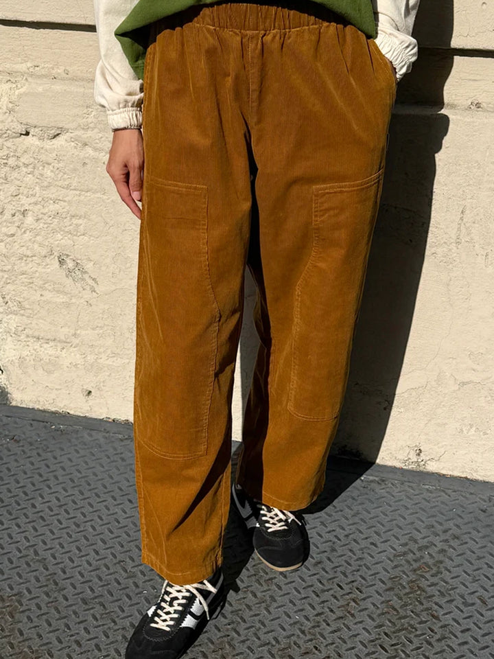 Model wearing Le Bon Shoppe Corduroy Gardener's Pants in Whiskey, featuring warm brown cotton corduroy, an elastic waistband, relaxed fit and carpenter-inspired patch pockets | Twentyseven Toronto