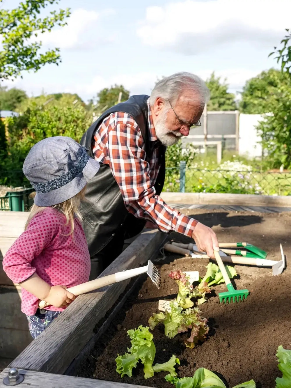 Man and child gardening together in a raised bed using Burstenhaus Redecker tools | Twentyseven Toronto