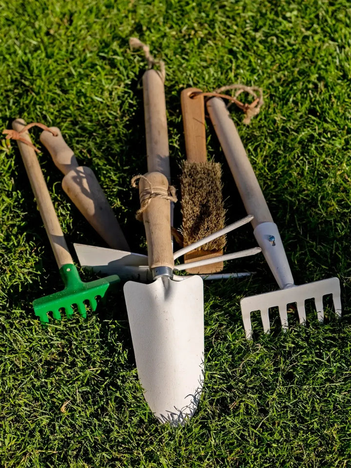 Set of Burstenhaus Redecker gardening tools including a trowel, rake, and cultivator on grass | Twentyseven Toronto