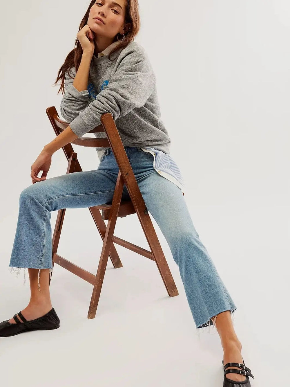 A model sits on a wooden chair wearing blue jeans and the black leather Free People Gemini Ballet Flats - Black | Twentyseven Toronto