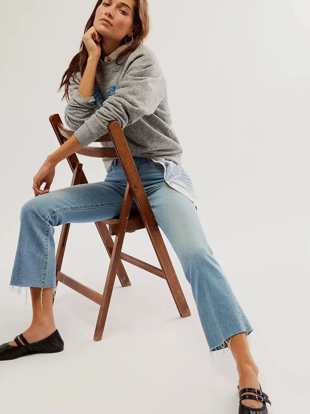 A model sits on a wooden chair wearing blue jeans and the black leather Free People Gemini Ballet Flats - Black | Twentyseven Toronto