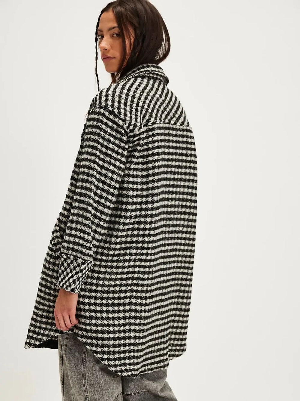 A rear three-quarter view displays the straight back yoke seam and longline silhouette of the textured Free People Get Around Houndstooth Shirt - Black + White | Twentyseven Toronto