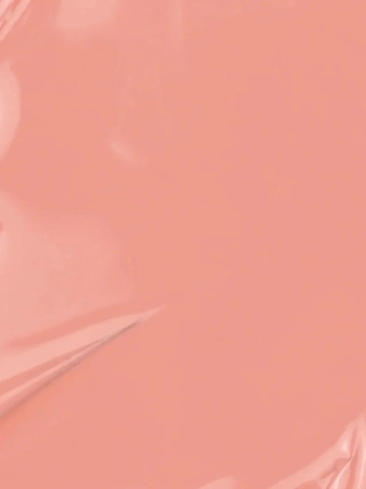 A full-frame texture shot showing the smooth, glossy, liquid surface of the soft peach-pink BKIND Nail Polish in Déjà Vu formula | Twentyseven Toronto
