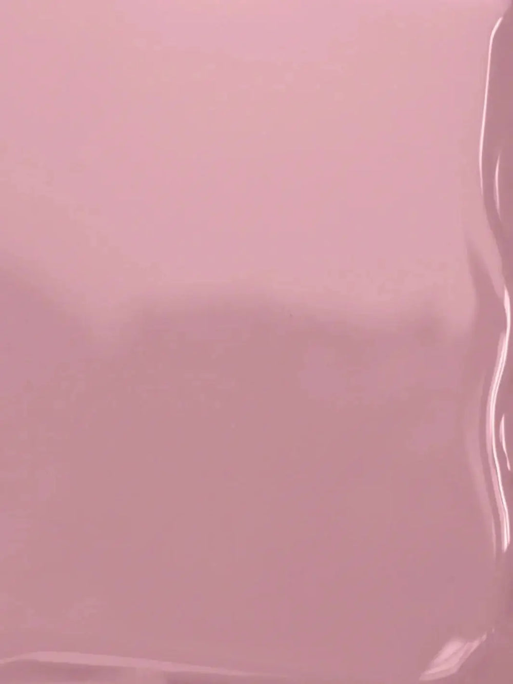 A close-up texture shot displaying the smooth, glossy, fluid surface of the mauve-pink BKIND Nail Polish in Wannabe formula | Twentyseven Toronto