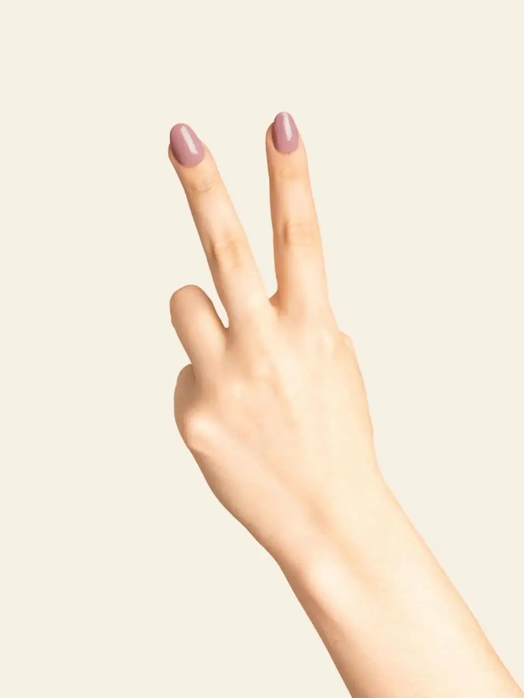 A hand holds up two fingers in a peace sign, showcasing a glossy manicure painted with BKIND Nail Polish in Wannabe | Twentyseven Toronto