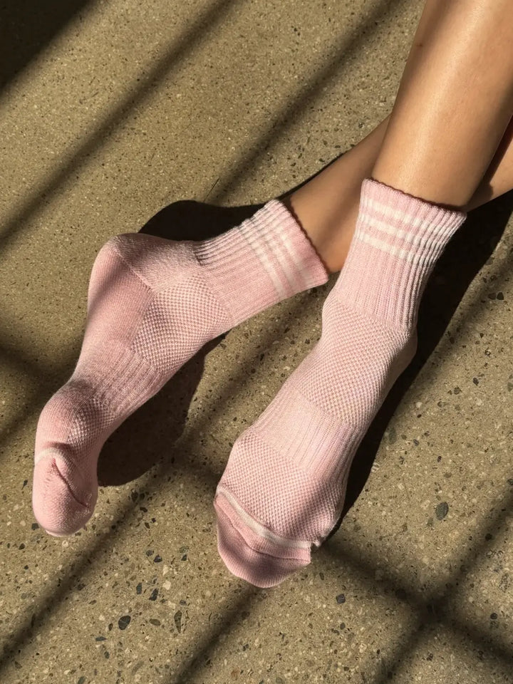 A person wears the light pink, ribbed Le Bon Shoppe Girlfriend Sock in Peony featuring white stripes at the ankle as sunlight filters across the floor | Twentyseven