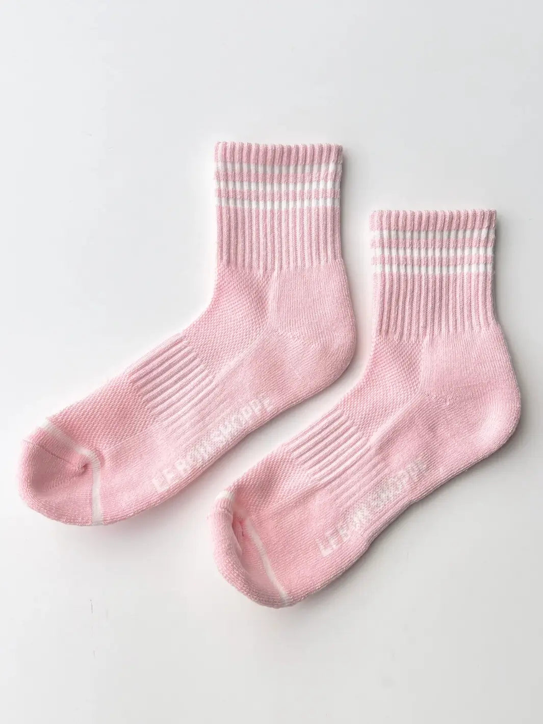 A pair of pink crew socks with white athletic stripes from the Le Bon Shoppe Girlfriend Sock in Peony collection is displayed flat on a plain white surface | Twentyseven