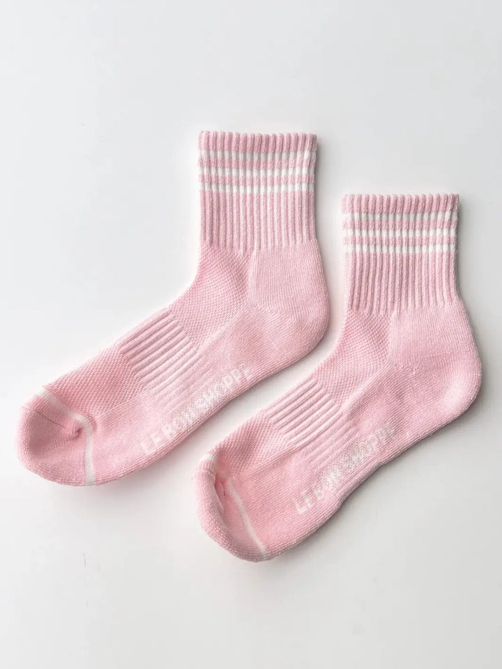 A pair of pink crew socks with white athletic stripes from the Le Bon Shoppe Girlfriend Sock in Peony collection is displayed flat on a plain white surface | Twentyseven