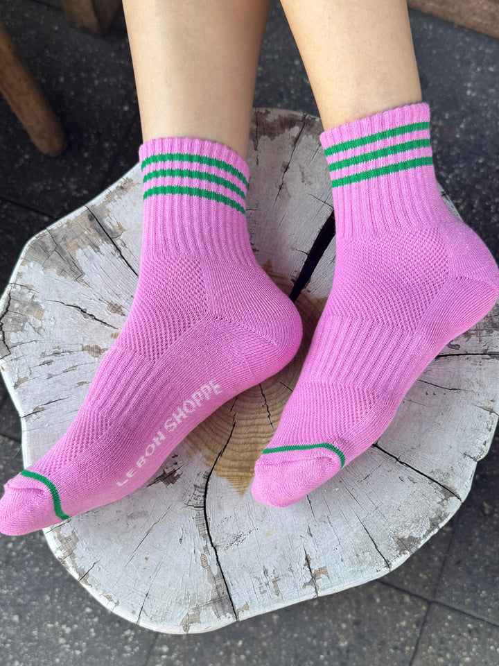 Le Bon Shoppe Girlfriend Socks in Rose Pink with green stripes, worn on a wooden stool | Twentyseven Toronto