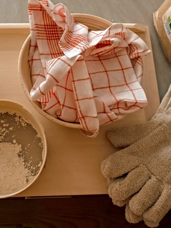 Checkered red towel from Burstenhaus Redecker in a basket with gloves on a wooden surface | Twentyseven Toronto