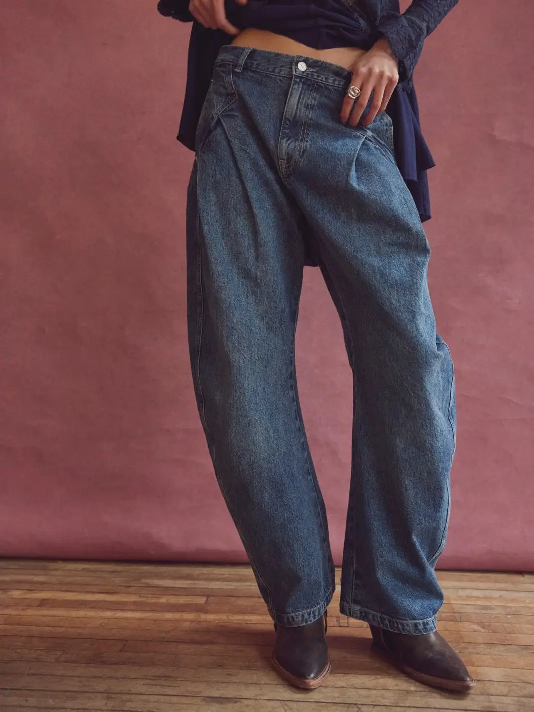 Low-angle front shot of the Free People We the Free Golden Hour Trouser Jeans in Deacon Blue highlighted against a textured pink studio wall | Twentyseven