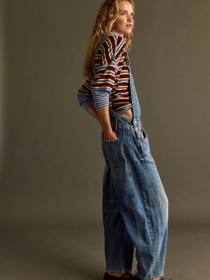 A side-angle studio portrait showcases the slouchy, comfortable fit of the Free People Good Luck Overall in Ultra Light Beam layered over a striped t-shirt | Twentyseven Toronto
