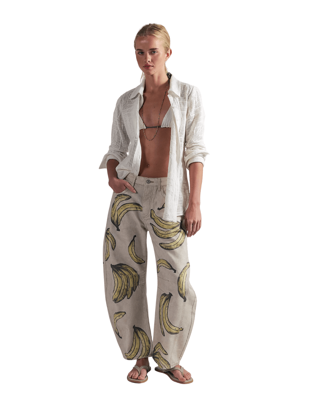 A model wearing the Free People Good Luck Printed Barrel Jeans in Go Bananas with an open white shirt and sandals | Twentyseven Toronto