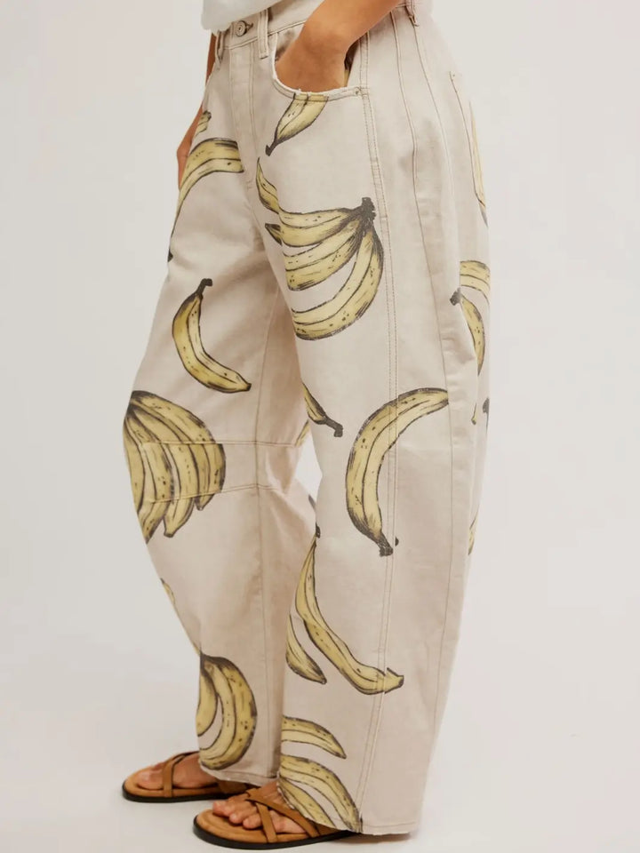 A side angled close-up view focusing on the curved leg silhouette and graphic banana pattern of the Free People Good Luck Printed Barrel Jeans in Go Bananas | Twentyseven Toronto
