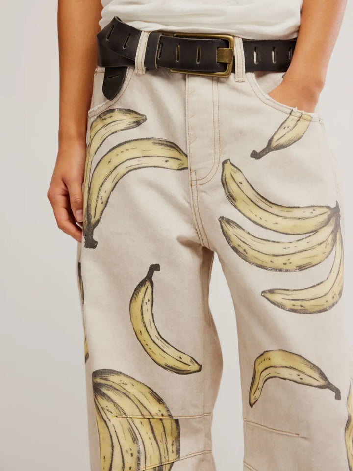 A close-up front view of the waistband and pocket details of the Free People Good Luck Printed Barrel Jeans in Go Bananas, styled with a black leather belt | Twentyseven Toronto