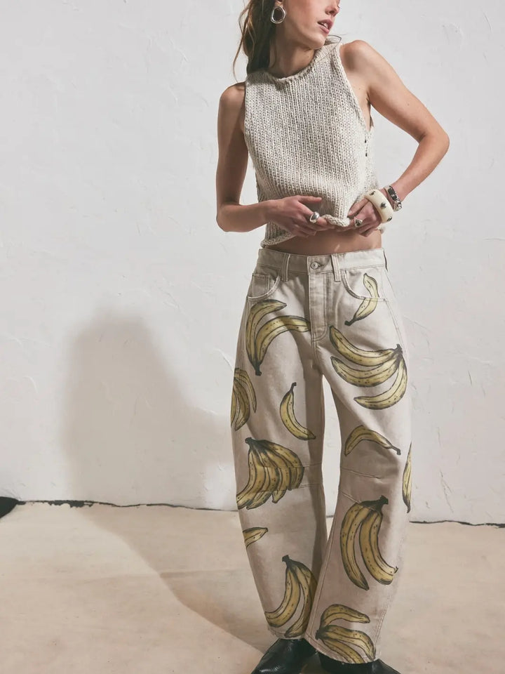 A model poses against a textured white wall wearing a sleeveless knit top and the Free People Good Luck Printed Barrel Jeans in Go Bananas | Twentyseven Toronto