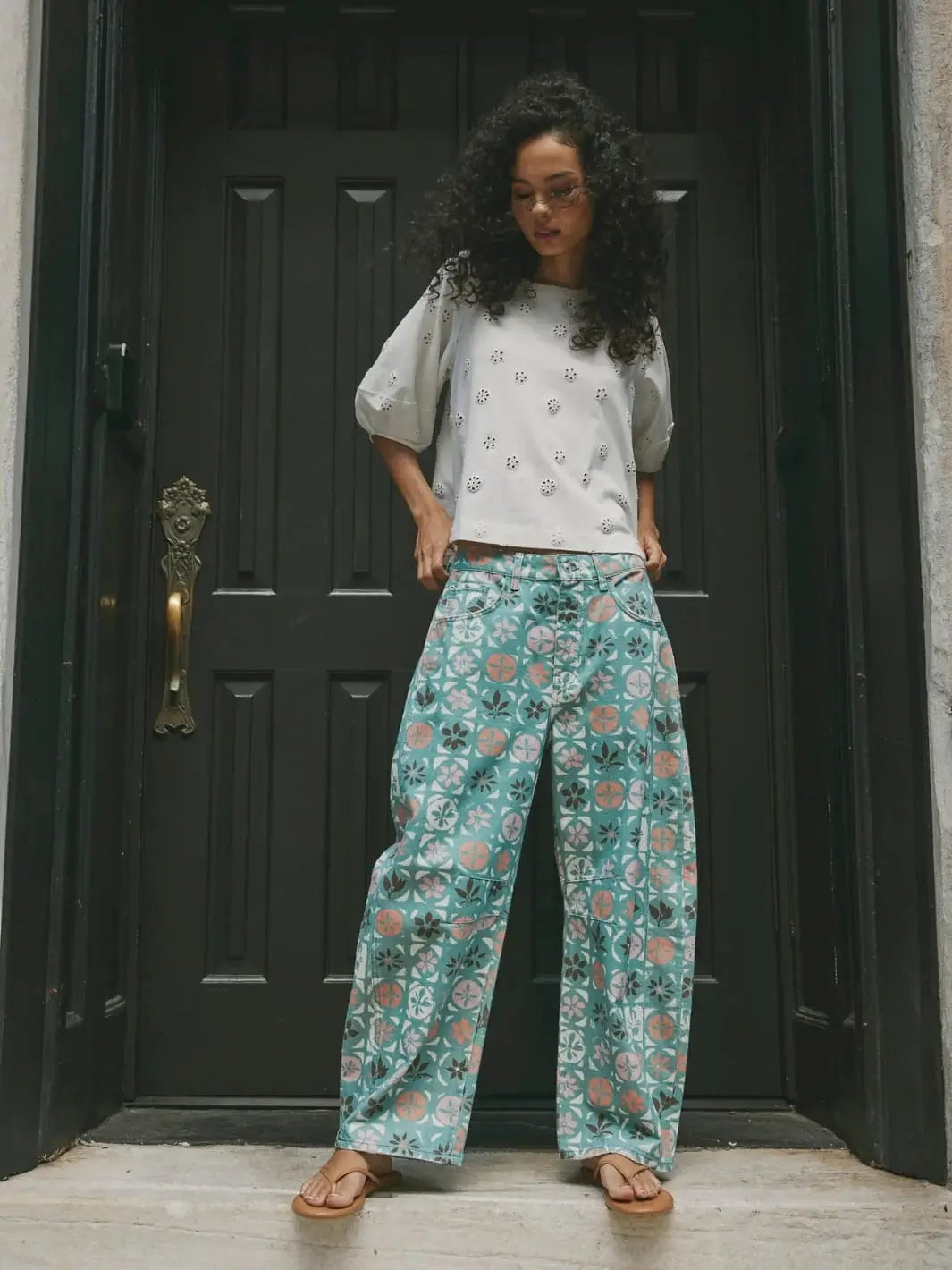 A full-length outdoor image showcases the unique geometric and floral print layout of the curved Free People Good Luck Printed Barrel Jeans in Jade Combo Ditsy Block | Twentyseven Toronto