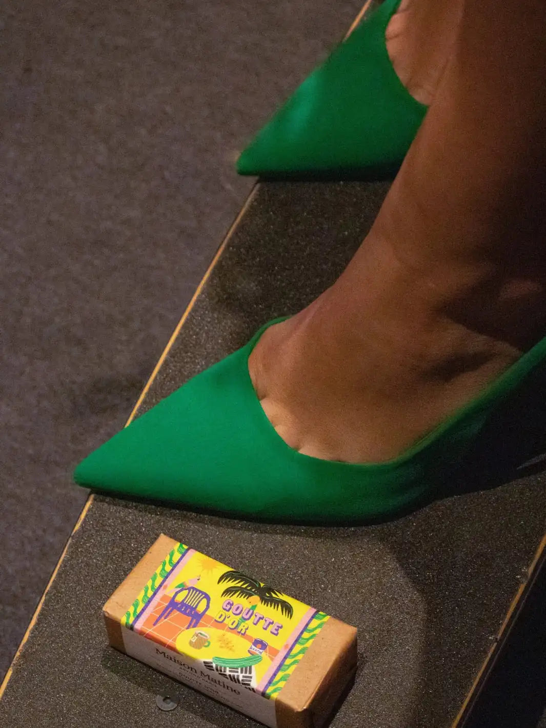 Green high-heeled shoes on a skateboard with Maison Matine Goutte d'Or Bar Soap beside it 100g | Twentyseven Toronto
