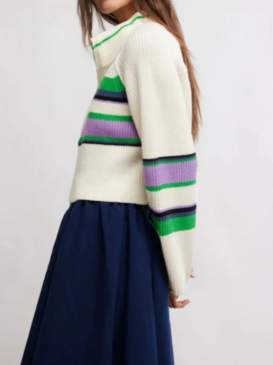 A side angle view shows a model wearing the cream, green, and purple striped Free People Greta Half Zip - Sugar Swirl Combo sweater paired with a dark blue skirt | Twentyseven Toronto