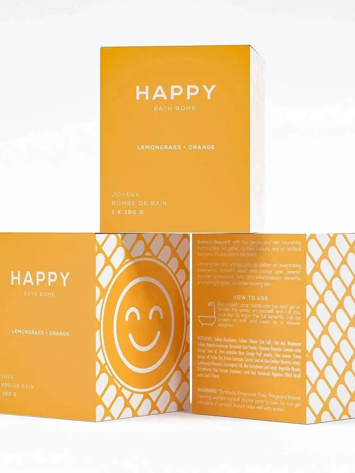 Three yellow boxes for the Bare Skin Bar HAPPY Bath Bomb are stacked to display the front product label, a side panel with a smiling face graphic, and the detailed ingredients on the back | Twentyseven Toronto