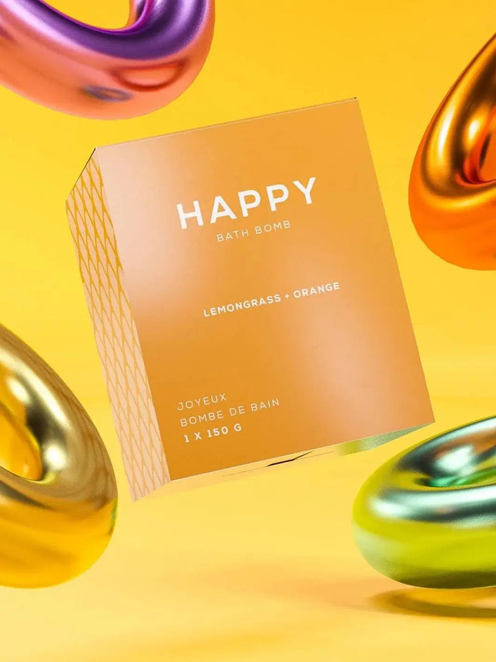 The yellow packaging for the Bare Skin Bar HAPPY Bath Bomb surrounded by floating, glossy metallic torus shapes against a solid yellow background | Twentyseven Toronto