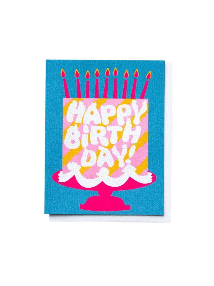 The Banquet Workshop Happy Birthday Pink Cake Dreams Note Card features a bold illustration of a pink and yellow striped birthday cake on a hot pink stand, complete with nine burning candles, set against a vibrant blue background | Twentyseven